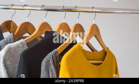 Herbst weiblichen gardera auf Kleiderbügeln der einen Pullover und eine Jacke von gelben und grauen Farben Stockfoto