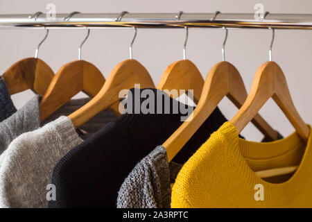 Herbst weiblichen gardera auf Kleiderbügeln der einen Pullover und eine Jacke von gelben und grauen Farben Stockfoto