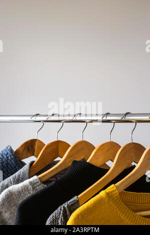 Herbst weiblichen gardera auf Kleiderbügeln der einen Pullover und eine Jacke von gelben und grauen Farben Stockfoto