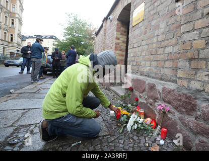 Halle, Deutschland. 10 Okt, 2019. Ein Mann stellt eine Kerze vor der Synagoge zu den bereits platzierten Blumen und Kerzen. Während der Angriffe in der Mitte der Halle/Saale in Sachsen-Anhalt gestern zwei Tote vor der Synagoge und in einem Kebab Snack Bar erschossen wurden. Kredite: Jan Woitas/dpa/Alamy leben Nachrichten Stockfoto
