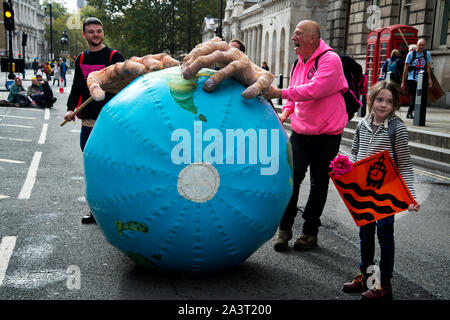 Aussterben Rebellion, Central London, 8. Oktober 2019 gierigen Händen Rollen einer fiktiven Planeten Erde unten Whitehall Stockfoto