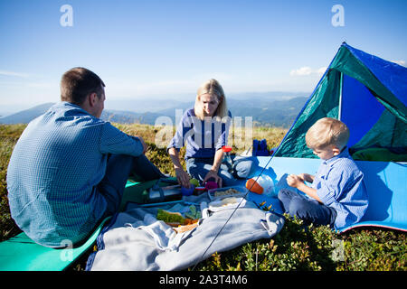 Happy Family Mit Frühstück vor dem Zelt auf einem Campingplatz an einem sonnigen Tag Stockfoto