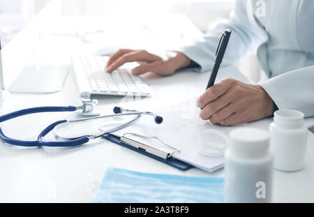 Frau Doktor schreibt einen medizinischen Bericht im Büro der Klinik. Stockfoto