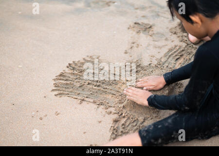 Wenig asiatischen Jungen spielt Sand am Strand. Ferienhäuser und Konzept entspannen.