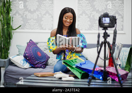 Cute afrikanische amerikanische Frau, die ein Video für Ihren Blog mit Stativ Digitalkamera montiert. Junge weibliche Blogger oder Vlogger auf Kamera. Stockfoto
