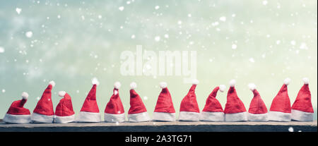 Hüte von Santa in einer Reihe auf einem rustikalen Holztisch, Panoramaaussicht Stockfoto