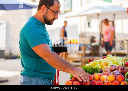 Mann wählt Obst und Gemüse auf dem Markt Stockfoto