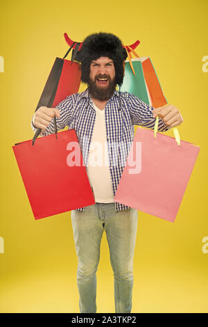 Taschen, seine schwarzen Freitag. Happy Hipster in Stier Hörner hat Holding Einkaufstaschen. Bärtiger Mann lächelnd mit Säcken aus Papier nach dem saisonalen Angebot. Die Einkäufe in bunten nicht Lebensmittelgeschäft Tragetaschen. Stockfoto