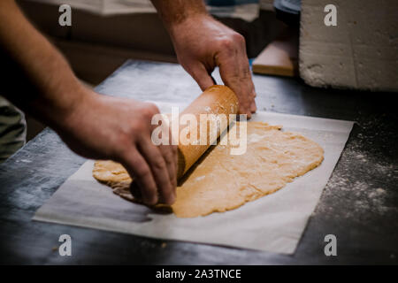 Bäcker Händen rollen Ingwer Teig auf einem dunklen Hintergrund. Nahaufnahme, Soft Focus. Seitenansicht, Draufsicht. Kopieren Sie Platz. Stockfoto