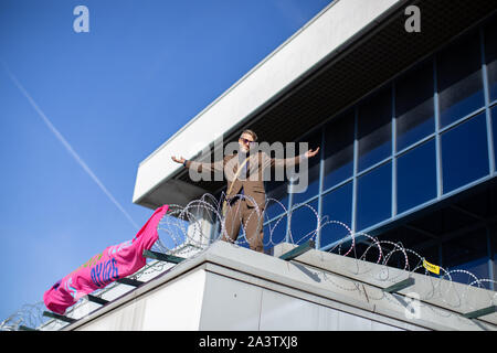 London, Großbritannien. 10 Okt, 2018. Eine Demonstrantin Gesänge Slogans während Gesten während der Demonstration am Flughafen auf dem Dach in London. Aussterben Rebellion Demonstranten plan Chaos am Flughafen London City für drei Tage zu verursachen, das Bewusstsein für den Klimawandel zu sensibilisieren. Credit: Ryan Ashcroft/SOPA Images/ZUMA Draht/Alamy leben Nachrichten Stockfoto