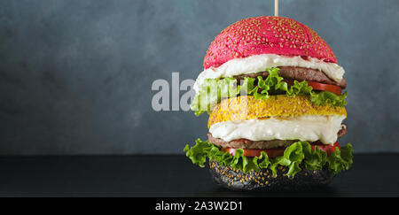 Banner der Großen Hamburger Brötchen mit verschiedenen Farben in Rot, Gelb und Schwarz mit Parmesan Sahne und Tomaten, Salat auf den Tisch. American foo Stockfoto