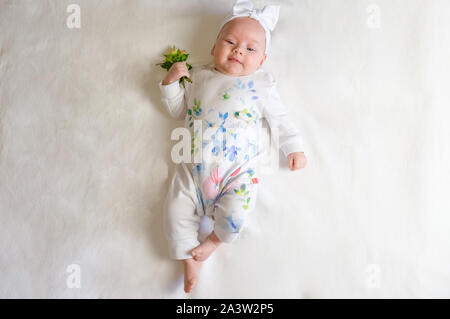 Das Baby Mädchen mit einem Verband auf seinem Kopf eine Rose in der Hand. Das baby lächelt. Stockfoto