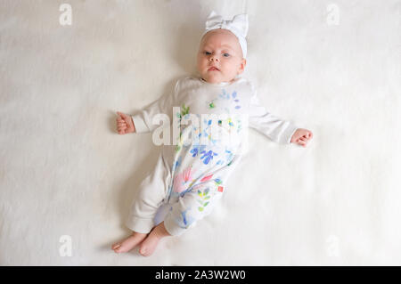 Das Baby Mädchen mit einem Verband auf seinem Kopf eine Rose in der Hand. Das baby lächelt. Stockfoto