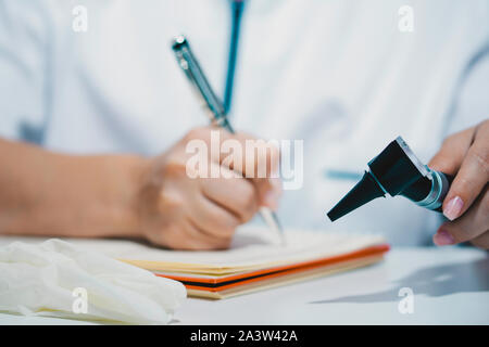 Frau Doktor mit otoskop in der Hand schreiben Rezept Stockfoto