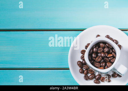 Weiße Tasse Kaffee mit Kaffeebohnen auf Blau Holz- Tabelle ausgefüllt, kopieren Raum Bild, Ansicht von oben Stockfoto