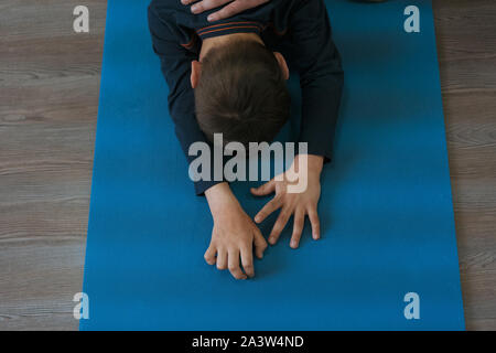 Kleine Junge ist in der Gymnastik auf eine Yogamatte, stehend auf Knien, ca. 5 Jahre alt. Stockfoto