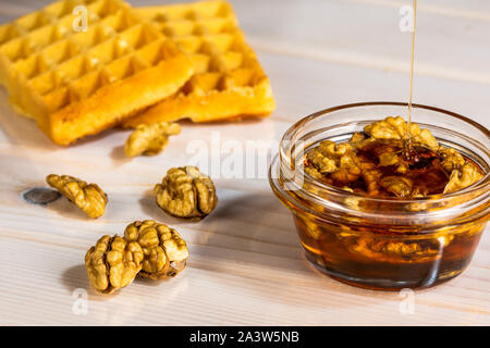 Die Walnüsse in Glas Schale mit Honig auf weiße Holztisch, Honig, Gießen, Raum Bild kopieren Stockfoto