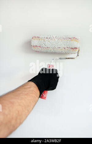 Bauarbeiter tun beenden Renovierung im Apartment. Professionelle Maler Auftragnehmer mit weißer Farbe bürstenrolle Malerei der Betonwand. Stockfoto