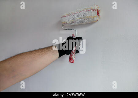Bauarbeiter tun beenden Renovierung im Apartment. Professionelle Maler Auftragnehmer mit weißer Farbe bürstenrolle Malerei der Betonwand. Stockfoto