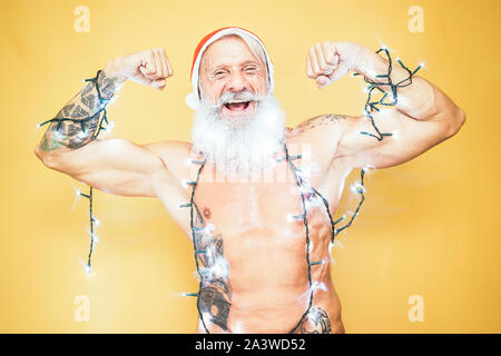 Happy fit santa claus ausgestattet mit weißen Weihnachten Lichter - trendige Bart hipster Senior tragen xmas Ausrüstung - Fest- und Feiertage Konzept Stockfoto