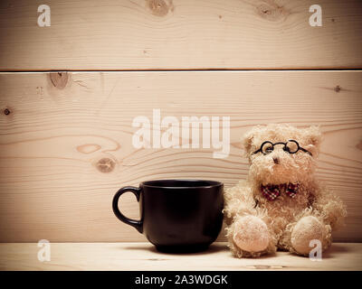 Kaffee mit Teddybär, der Hintergrund ist eine braune hölzerne Platte. (Vintage) (Abbildung mit Platz für Text) Stockfoto