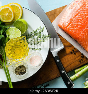Frischer Lachs Schicht auf einer hölzernen Schneidebrett mit frischen Kräutern und Spargel auf den Tisch. Kochen Rezept. essen Hintergrund. Frischer Fisch Produkt Stockfoto