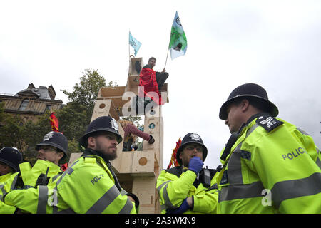 Die Demonstranten auf einem hölzernen Struktur auf der Verkehrsinsel zwischen Northumberland Avenue und der Strang in Trafalgar Square während des vierten Tag der Auslöschung Rebellion (XR) Protest in Westminster, London. Stockfoto