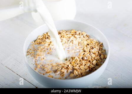 Milch über einer Schüssel voll mit Müsli gegossen wird, Stockfoto