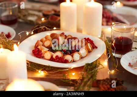 In der Nähe von kleinen Kuchen mit Beeren auf den Tisch dekoriert mit Kerzen und Lichter für Urlaub Abendessen serviert Stockfoto