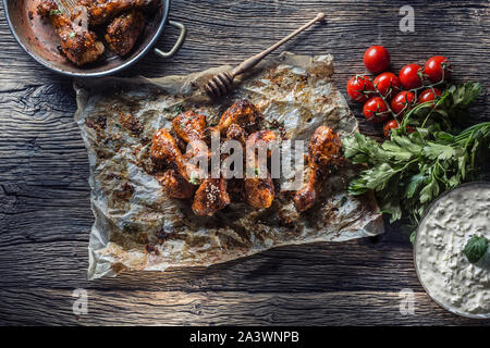 Gebratene Hähnchenschenkel Grill auf gebackene Papier mit Tzatziki sauce Tomaten und Petersilie Kräuter. Stockfoto