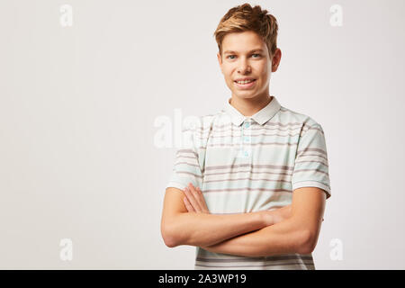 Porträt der jungen mit blonden Haaren in Casual T-shirt Stand mit verschränkten Armen und lächelnd an der Kamera auf weißem Hintergrund Stockfoto
