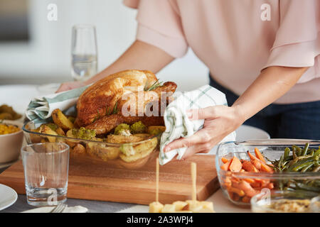 In der Nähe von Frau setzt das Gericht mit gebratenem Truthahn und Kartoffeln auf dem Esstisch für Thanksgiving Tag Stockfoto