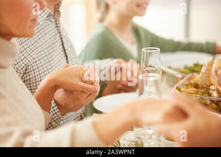 Nahaufnahme der Familie am Esstisch urlaub Tabelle und halten sich an den Händen sie beten vor dem Essen sitzen Stockfoto