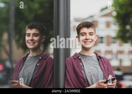 Portrait von Geschlechtsneutral junger Erwachsener mit Smartphone Stockfoto