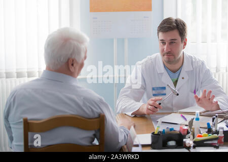 Belarus, Gomel, 31. Mai 2017. Central Hospital. Arzt und Patient. Ein älterer Mann in der Arztpraxis. Der Mann an der Rezeption im Medical offi Stockfoto