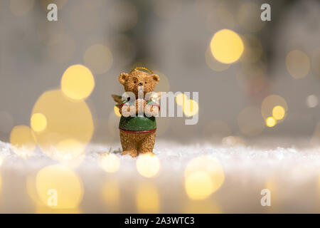 Dekorative Figuren aus einem Thema Weihnachten. Figurine eines süßen Bär mit Angel Wings. Festliches Dekor, warme Bokeh leuchtet. Stockfoto