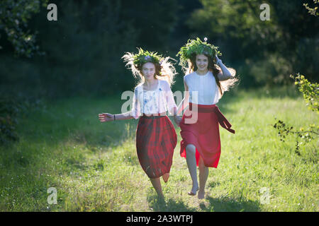 Belarus, die Stadt Gomel, Juli 07, 2018. Ferienwohnung Ivan Kupala. Mädchen in der Slawischen Kleidung mit einem Kranz auf dem Kopf laufen über ein grünes Feld. Schönheit Stockfoto