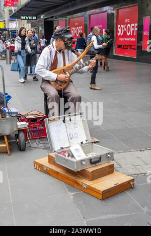 Männliche Gaukler das Tragen einer Gasmaske spielen eine elektrische Gitarre in der Bourke Street Mall Melbourne, Victoria, Australien. Stockfoto