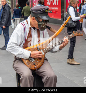 Männliche Gaukler das Tragen einer Gasmaske spielen eine elektrische Gitarre in der Bourke Street Mall Melbourne, Victoria, Australien. Stockfoto
