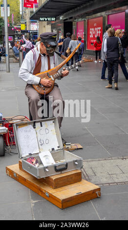 Männliche Gaukler das Tragen einer Gasmaske spielen eine elektrische Gitarre in der Bourke Street Mall Melbourne, Victoria, Australien. Stockfoto