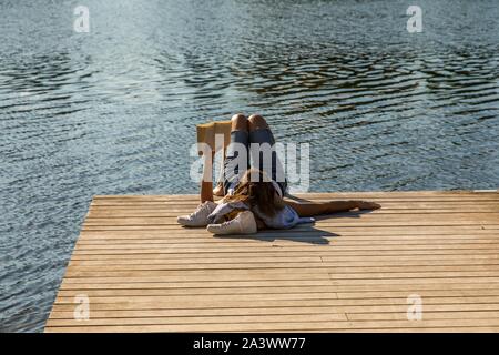 Junge Frau mit einem Buch auf einem hölzernen Steg AM UFER DER ALLIER, Erholung, Freizeit, Freiheit, Stille, Vichy, ALLIER, Auvergne, RHÔNE-ALPES, Frankreich Stockfoto