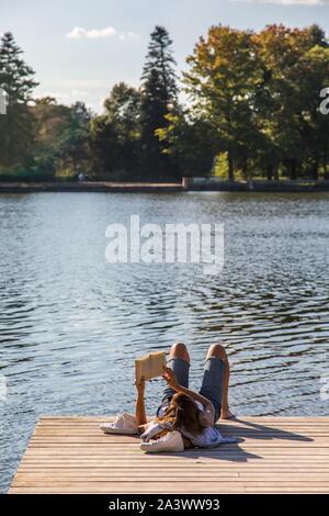 Junge Frau mit einem Buch auf einem hölzernen Steg AM UFER DER ALLIER, Erholung, Freizeit, Freiheit, Stille, Vichy, ALLIER, Auvergne, RHÔNE-ALPES, Frankreich Stockfoto