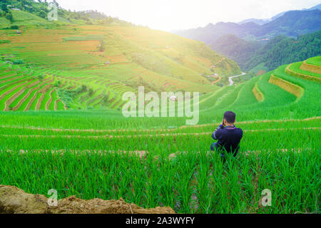 Junge Männer sitzen und die Bilder schön terrassierten Reisfelder Feld- und Berglandschaft in Me Cang Chai und SAPA VIETNAM Sonnenlicht und Flare b Stockfoto