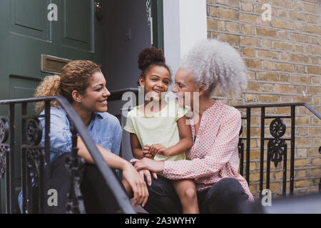 Drei Generationen von Frauen sitzen außerhalb der Familie zu Hause Stockfoto
