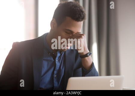 Frustriert, betonte Schwarz Unternehmer fühlen sich die Belastung der Augen Kopfschmerzen bei der Arbeit Stockfoto