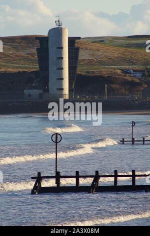 Hafen Aberdeen Control Tower, über dem Strand mit hölzernen Buhnen und Nordsee Wellen. Schottland, Großbritannien. Stockfoto