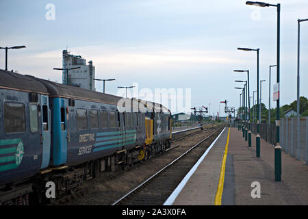 Zug unter der Leitung von einem Jahrgang Klasse 37 Dieselmotor über den Bahnhof Lowestoft ein traditionelles semaphore Signal abweichen können in der Ferne gesehen werden. Stockfoto