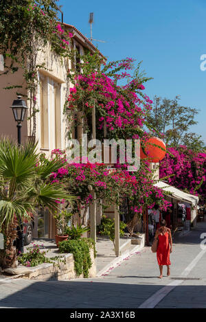 Rethymno, Kreta, Griechenland. September 2019. Die Frau im roten Kleid zu Fuß durch eine farbenfrohe Einkaufsviertel im Zentrum von Rethymnon, Kreta. Stockfoto