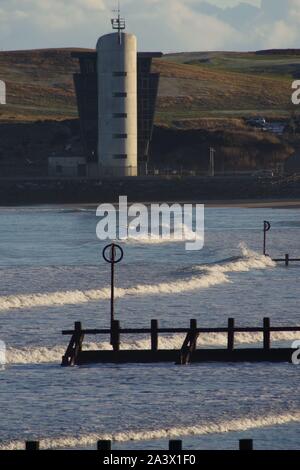 Hafen Aberdeen Control Tower, über dem Strand mit hölzernen Buhnen und Nordsee Wellen. Schottland, Großbritannien. Stockfoto