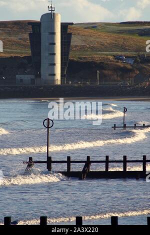 Hafen Aberdeen Control Tower, über dem Strand mit hölzernen Buhnen und Nordsee Wellen. Schottland, Großbritannien. Stockfoto